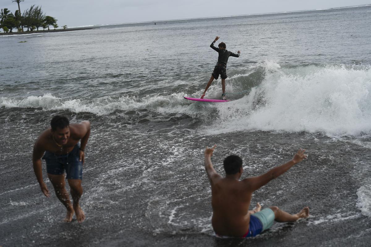 Kids surf small waves along the beach after school in Teahupo’o, Tahiti, French Polynesia. 