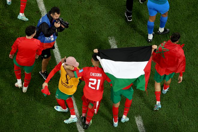 Morocco players hold up a flag in support of Palestine as they celebrate their 1-0 victory in the FIFA World Cup Qatar 2022 quarter final match between Morocco and Portugal.