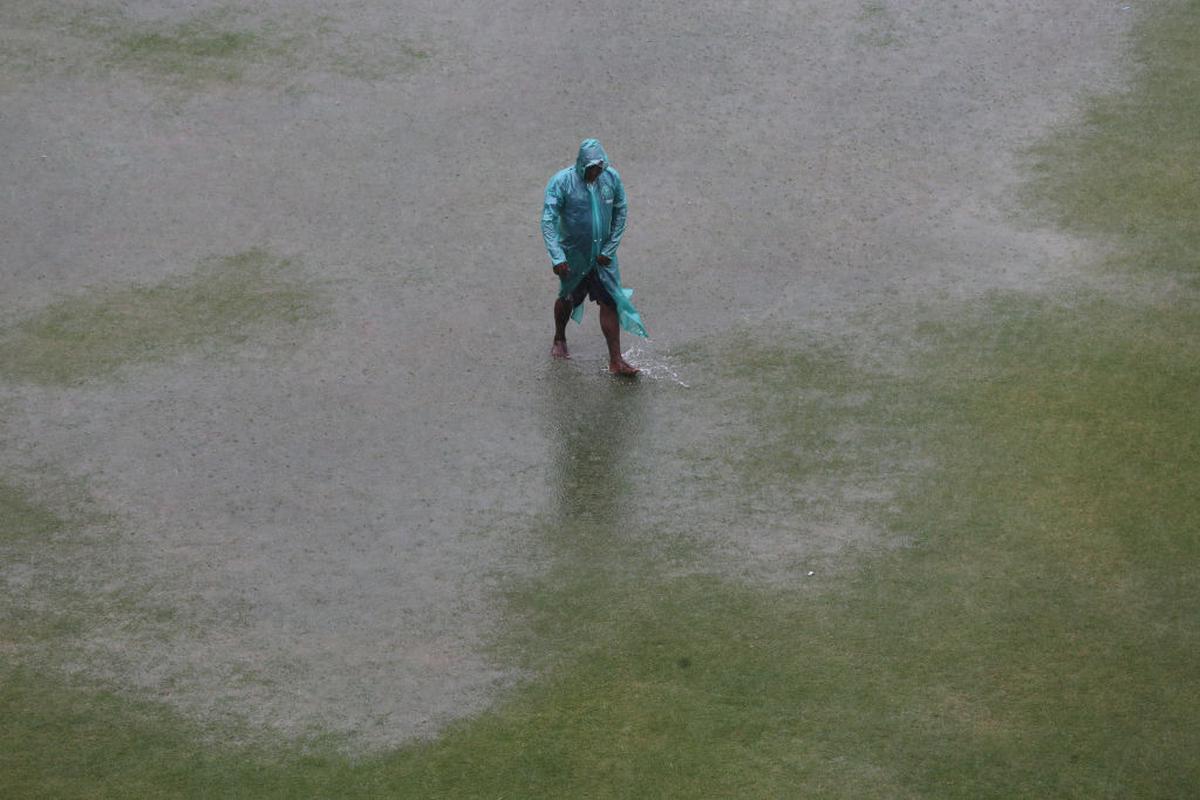 Ground staff walk across a puddle of water in the outfield following heavy rain which stopped the warm up match between South Africa and Afghanistan.