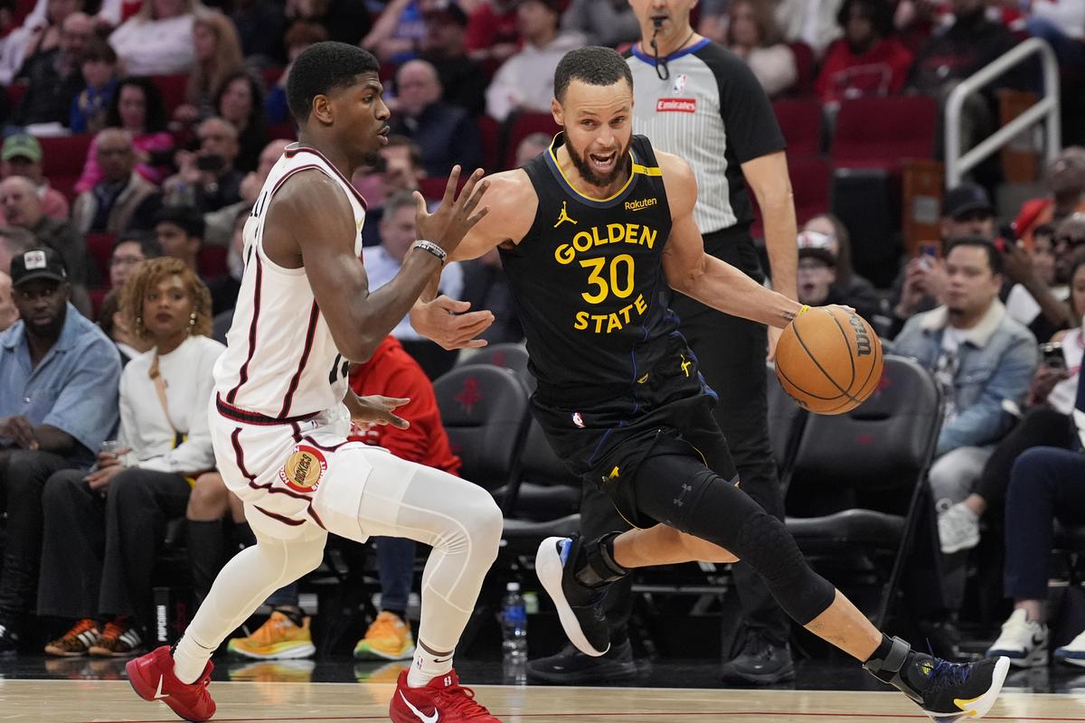 Golden State Warriors’ Stephen Curry (30) drives around Houston Rockets’ Nate Williams defends during the second half of an NBA basketball game.