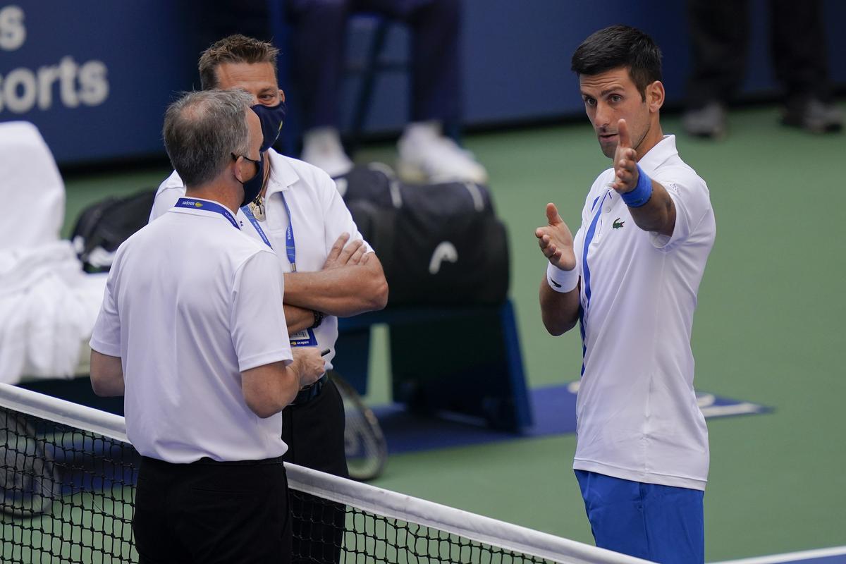 Novak Djokovic, of Serbia, talks with the umpire after inadvertently hitting a line judge with a ball after hitting it in reaction to losing a point against Pablo Carreno Busta, of Spain, during the fourth round of the US Open tennis championships.