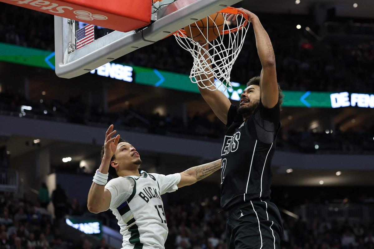 Cameron Johnson (right) of Brooklyn Nets dunks in front of Ryan Rollins of the Milwaukee Bucks during the second half of an NBA game.