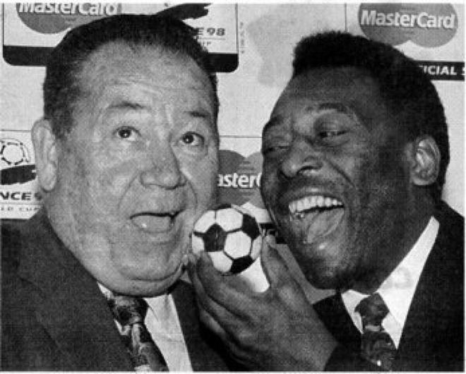 Football legend Pele (right) of Brazil feeds Just Fontaine, of France, a cake shaped. like a soccer ball on Sunday in Paris during the 4Oth anniversary celebration of the 1958 Vf’orld Cup in Sweden. Brazil won the Cup, while Fontaine scored a record 13 goals in the tournament.