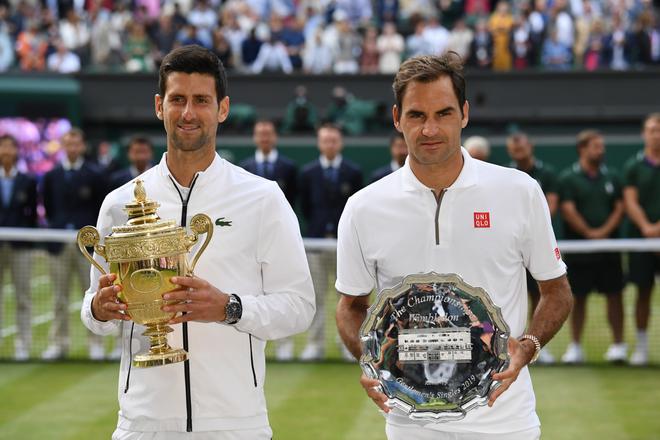 Serbia’s Novak Djokovic (L) poses with the winner’s trophy and Switzerland’s Roger Federer (R) holds the runners up plate during the presentation after the men’s singles final on day thirteen of the 2019 Wimbledon Championships at The All England Lawn Tennis Club in Wimbledon, southwest London, on July 14, 2019.