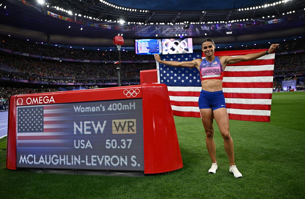 Sydney McLaughlin-Levrone of United States celebrates with her national flag after winning 400m hurdles gold and setting new world record.