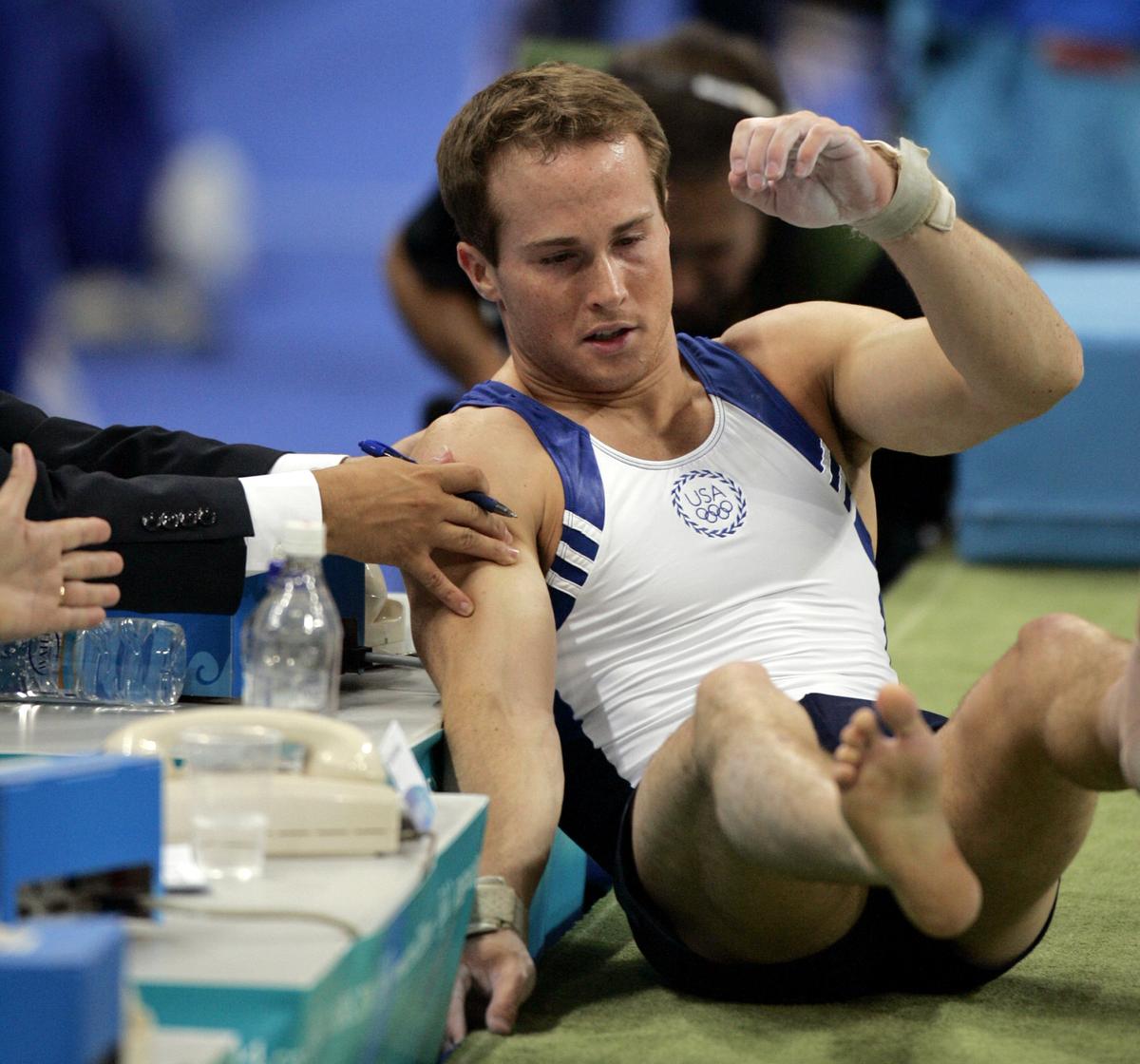 A judge reaches out to help Paul Hamm, of the United States, after he fell on the landing of his vault during the men’s gymnastics individual all-around final at the 2004 Olympic Games in Athens.