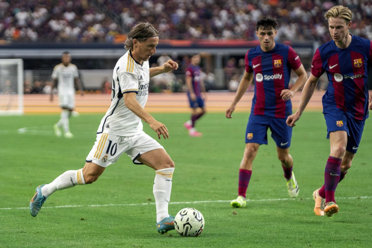 Real Madrid midfielder Luka Modric (10) dribbles against FC Barcelona midfielder Frenkie de Jong, right, and defender Andreas Christensen, center, during the second half of a Champions Tour football match.