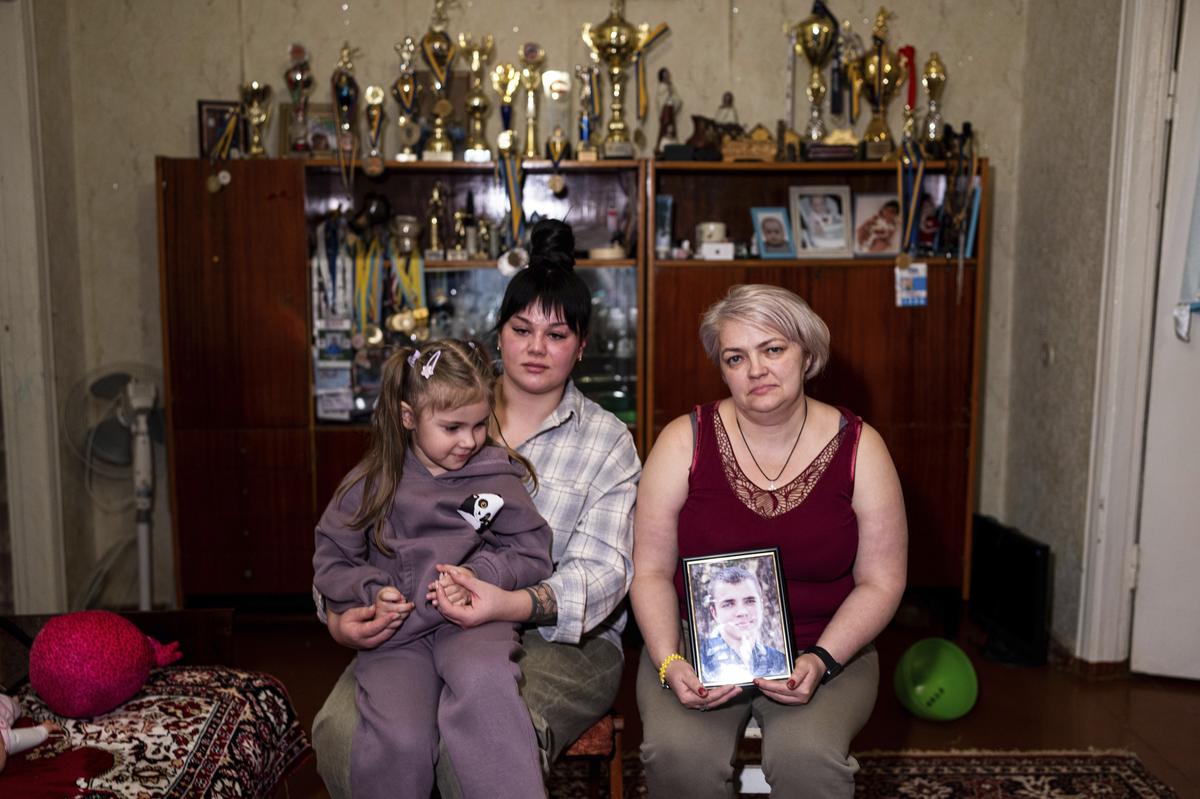 Vasilisa, with her mother, Polina Ihrak, and grandmother, Svitlana Halinicheva, sit together for a photo after returning home from a boxing tournament in honor of her father Maksym Halinichev, who was killed during fighting with Russian forces in March 2023, in Shostka, Sumy region, Ukraine on Sunday, Feb. 4, 2024. (AP Photo/Evgeniy Maloletka)