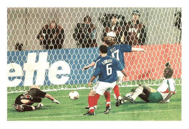 Senegalianul Papa Bouba Diop (dreapta) glisează mingea pe lângă portarul francez Fabien Barthez, în timp ce fundașii Youri Djorkaeff (6) și Emmanuel Petit se grăbesc puțin prea târziu, în meciul de deschidere al Cupei Mondiale din 2002. 
