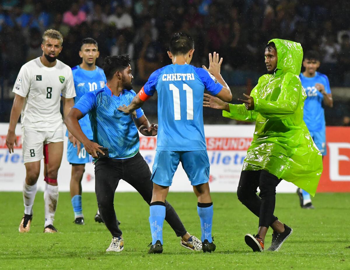 Security personnel chase a pitch invader who entered the field of play to get a close glimpse of India football captain Sunil Chhetri during India’s encounter against Pakistan at the SAFF Championship in Bengaluru on Wedmesday.  