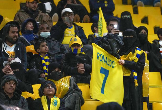 A Saudi woman holds a flag with a Cristiano Ronaldo shirt, a new member of Al Nassr club, as she attends her team match against Al Tai in the Saudi League at Marsool Park in Riyadh on January 6, 2023. 