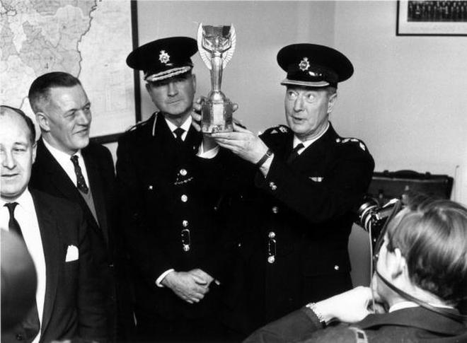 28th March 1966:  At Cannon Row police station, London, Chief Superintendent William Gilbert lifts the Jules Rimet trophy.  With him are Detective Chief Inspector William Little, (left), and Commander John Lawler. The World Cup was stolen from the National Stamp Exhibition and found by Pickles, a dog out walking with his owner in Norwood, south London.  