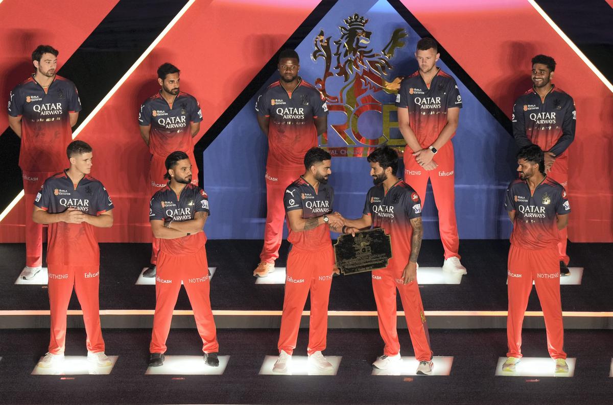 Royal Challengers Bengaluru’s Virat Kohli presents a shield to skipper Rajat Patidar during the RCB Unbox event at M. Chinnaswamy Stadium in Bengaluru on Monday.