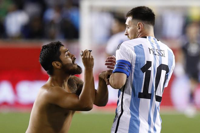 Argentina’s Lionel Messi reacts as a fan ran on the pitch to ask for his autograh during the international friendly football match between Argentina and Jamaica at Red Bull Arena in Harrison, New Jersey, on September 27, 2022. 