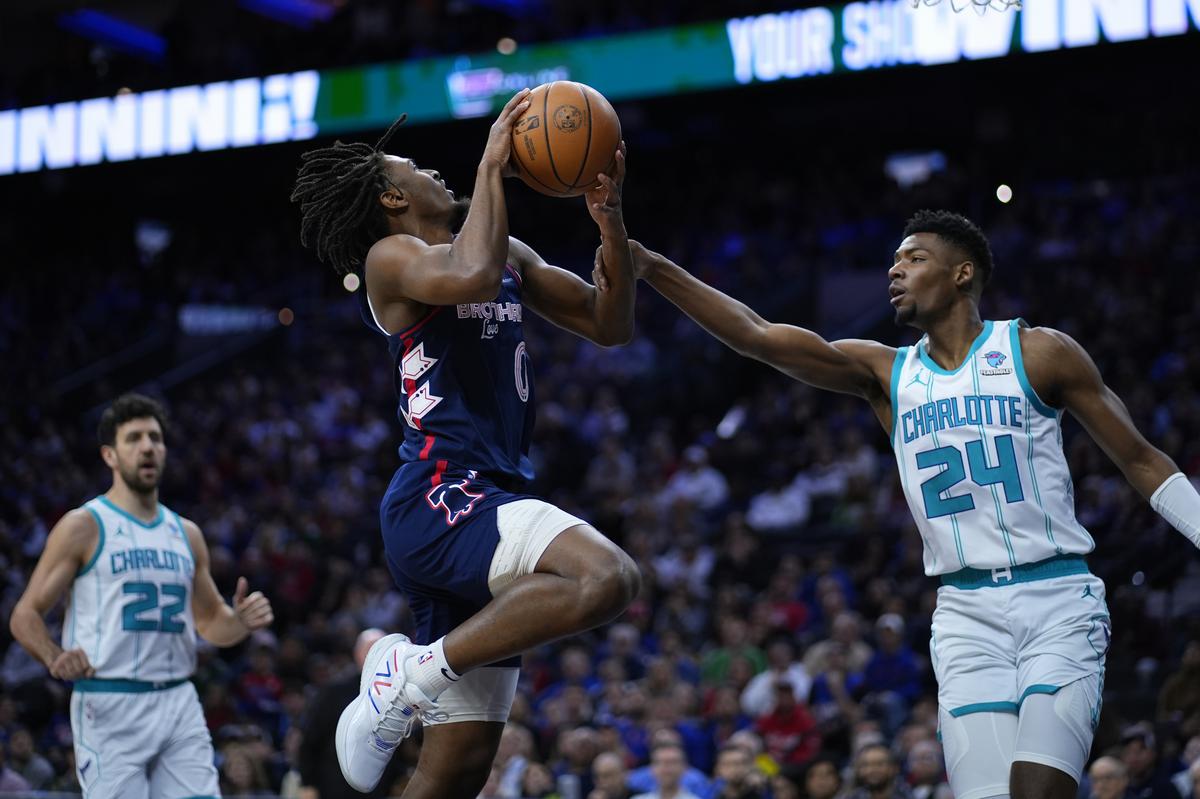 Philadelphia 76ers’ Tyrese Maxey, center, goes up for a shot against Charlotte Hornets’ Brandon Miller during the first half of an NBA basketball game.