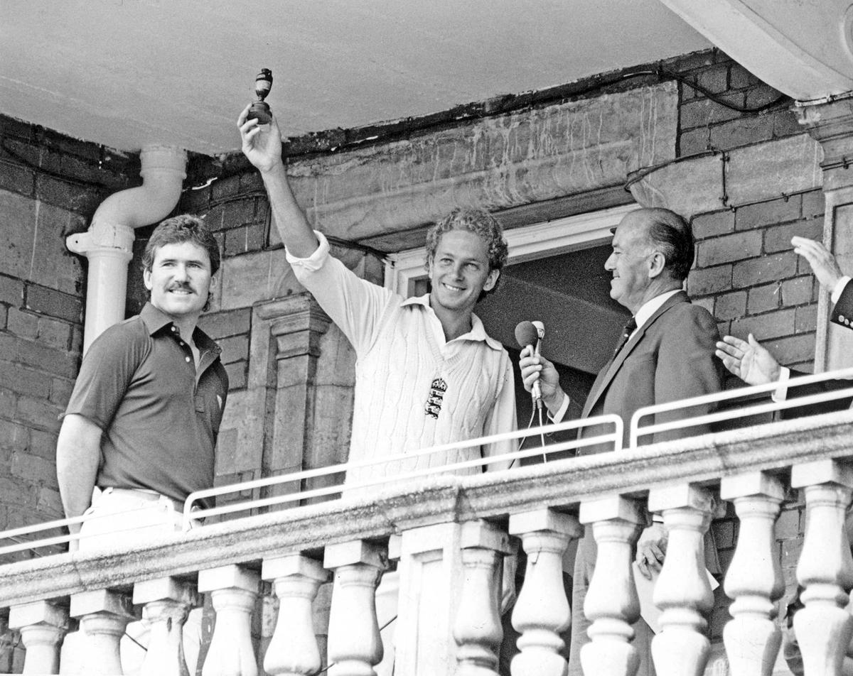 Ashes reverie: David Gower, England’s debonair captain, stands tall on the Oval balcony, cradling the Ashes urn — the gleaming symbol of a summer triumph. The 3-1 series win in 1985 is his crowning moment. Beside him, Allan Border embodies the stoic dignity of defeat.
