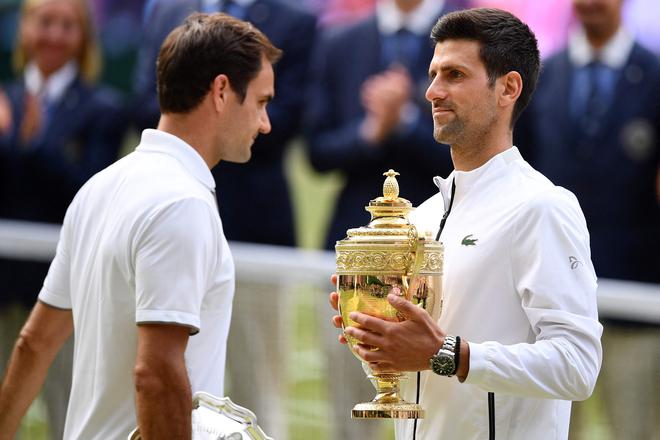 Djokovic (R) with the winner’s trophy after beating Roger Federer in the 2019 Wimbledon Championships.