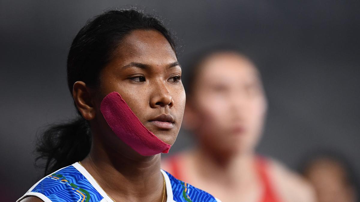 Athlete Swapna Barman with a gold medal and political posters in the background