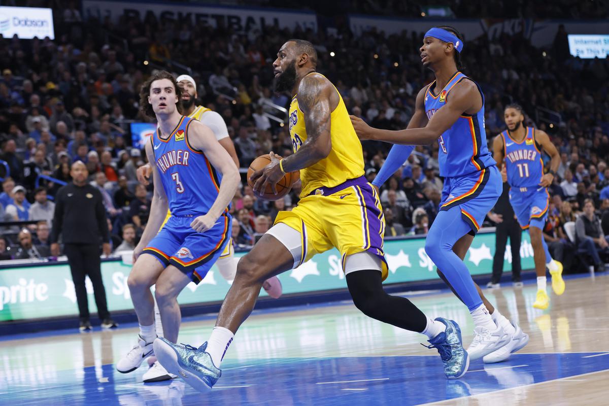 Los Angeles Lakers forward LeBron James, middle, drives to the basket as Oklahoma City Thunder guards Josh Giddey, left, and Shai Gilgeous-Alexander defend during the first half of an NBA basketball game Thursday, Nov. 30, 2023, in Oklahoma City. 