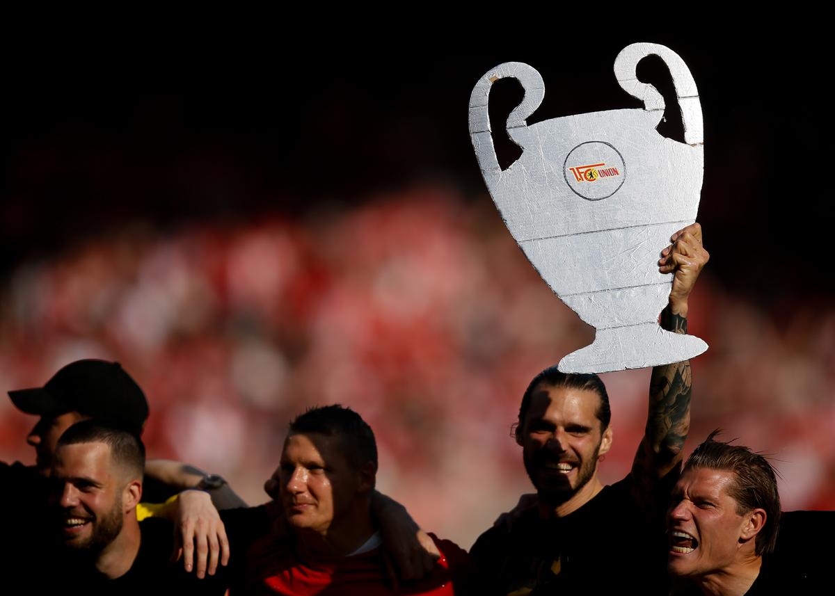 BERLIN, GERMANY - MAY 27: the team of Union Berlin with Christopher Trimmel who holds up the champions league trophy and Kevin Behrens (R) celebrate their teams win during the Bundesliga match between 1. FC Union Berlin and SV Werder Bremen at Stadion an der alten Försterei on May 27, 2023 in Berlin, Germany. (Photo by Selim Sudheimer/Getty Images)