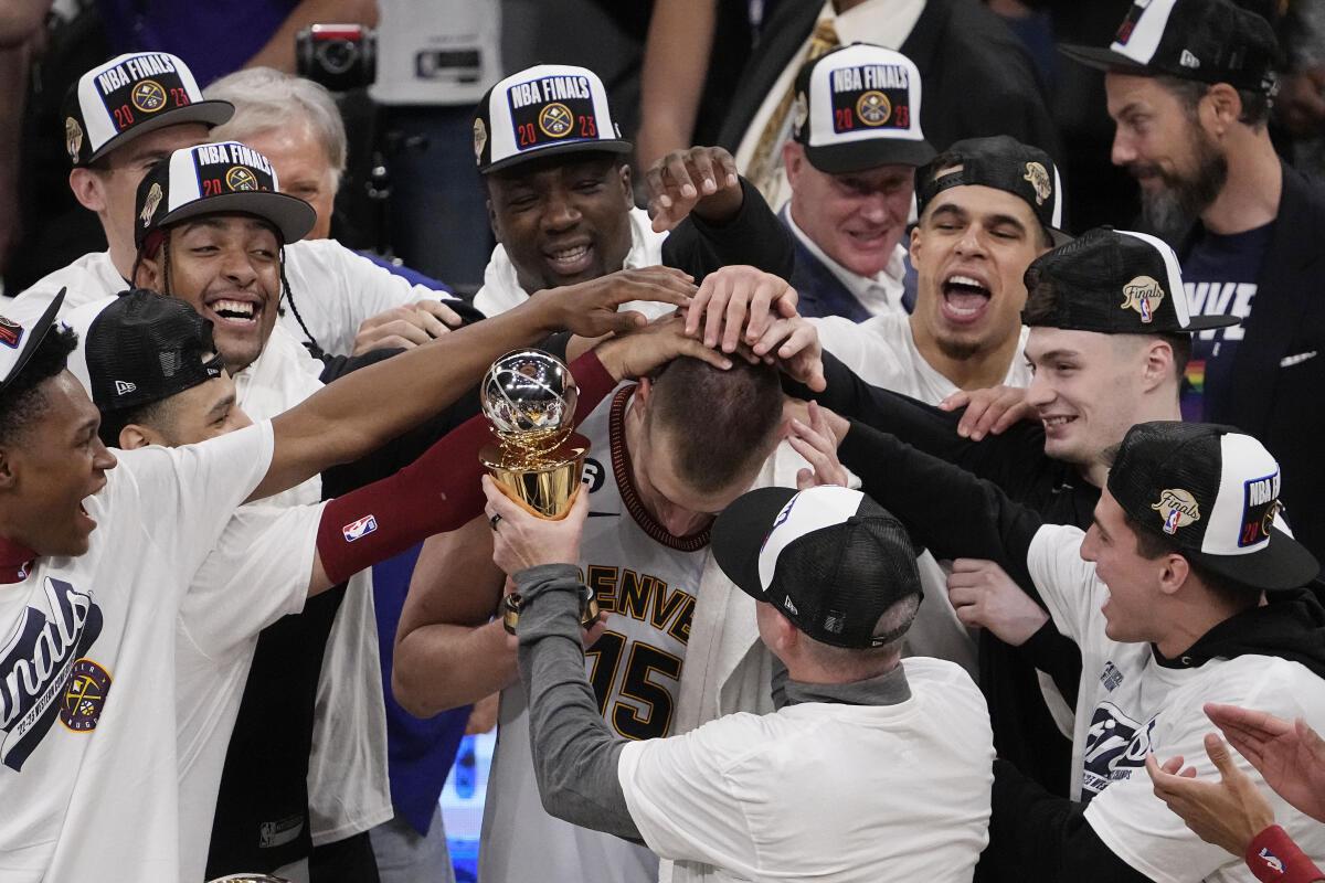 Denver Nuggets center Nikola Jokic, center, gets a pat on the head from teammates after receiving the series MVP trophy after defeating the Los Angeles Lakers in Game 4 of the NBA basketball Western Conference Final series.