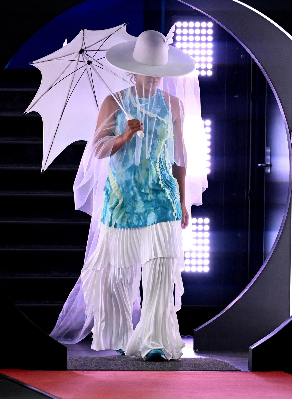 A superestrela japonesa apareceu na Rod Laver Arena carregando uma sombrinha branca com chapéu de abas largas e véu longo combinando, usando um vestido turquesa sem mangas sobre calças brancas pregueadas.