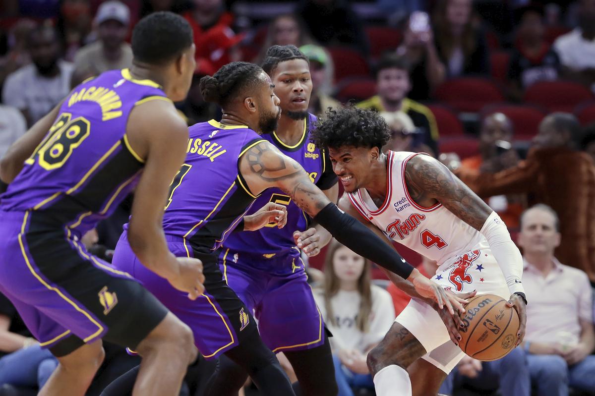 Houston Rockets guard Jalen Green tries to protect the ball from Los Angeles Lakers’, from left, forward Rui Hachimura, guard D’Angelo Russell and forward Cam Reddish during the first half of an NBA basketball game.