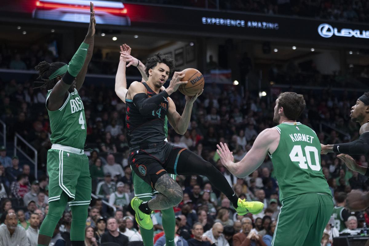 Washington Wizards guard Jules Bernard (14) looks to pass the ball while crowded by Boston Celtics guard Jrue Holiday (4) and forward Sam Hauser, back, and center Luke Kornet (40) during the first half of an NBA basketball game.