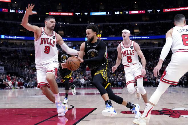 Golden State Warriors guard Stephen Curry (second from left) drives to the basket against Chicago Bulls center Nikola Vucevic. 