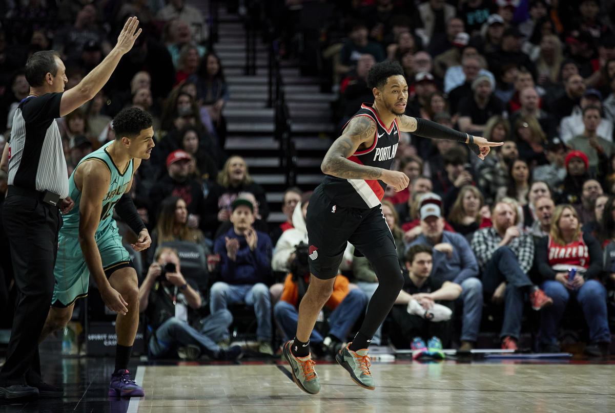 Portland Trail Blazers guard Anfernee Simons, right, reacts after making a three-point basket in front of Charlotte Hornets guard Josh Green during the second half of an NBA basketball game.