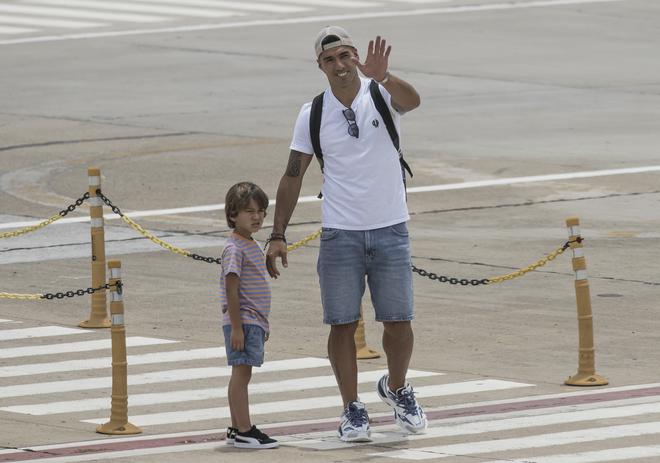 Uruguay’s Luis Suarez waves, accompanied by one of his sons, after they arrive at Islas Malvinas international airport in Rosario, Santa Fe province, Argentina, on December 22, 2022, before heading to the home of Argentina’s Lionel Messi. 
