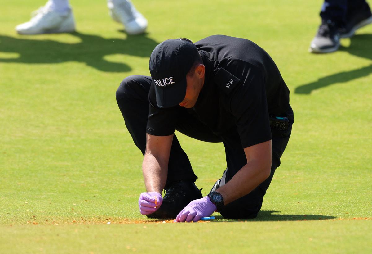 A police officer inspects the orange substance on the 17th green following a Just Stop Oil protest during the second round of The Open on Friday.