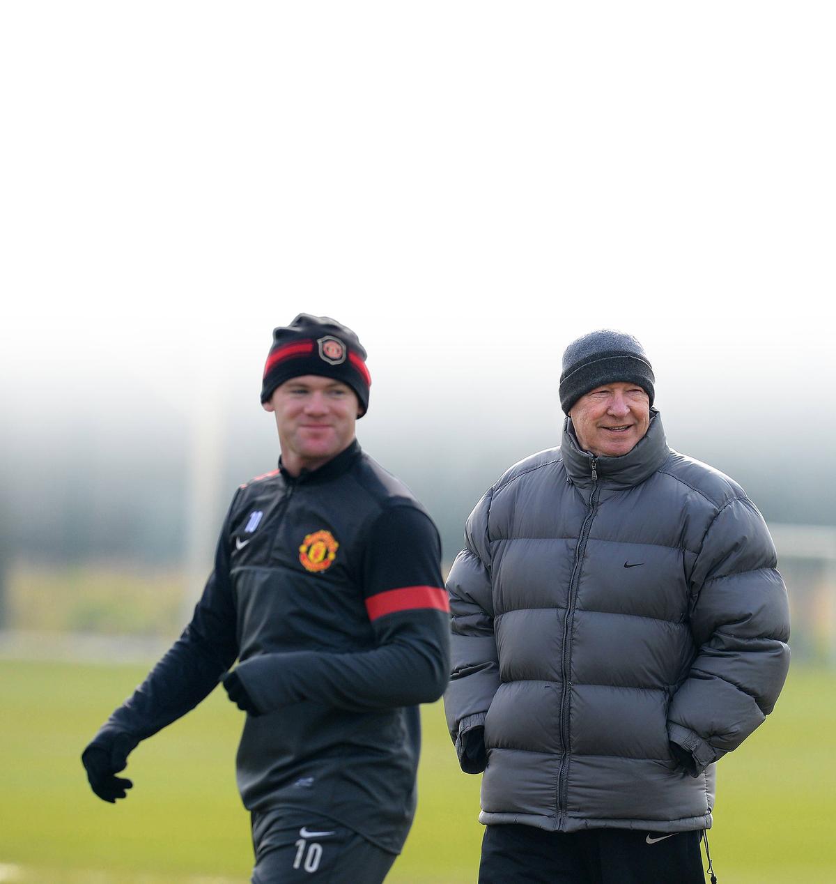 (FILES) In a file pictuer taken on March 4, 2013 Manchester United manager Alex Ferguson (R) and Manchester United’s English forward Wayne Rooney (L) attend a training session at the Carrington training complex. 