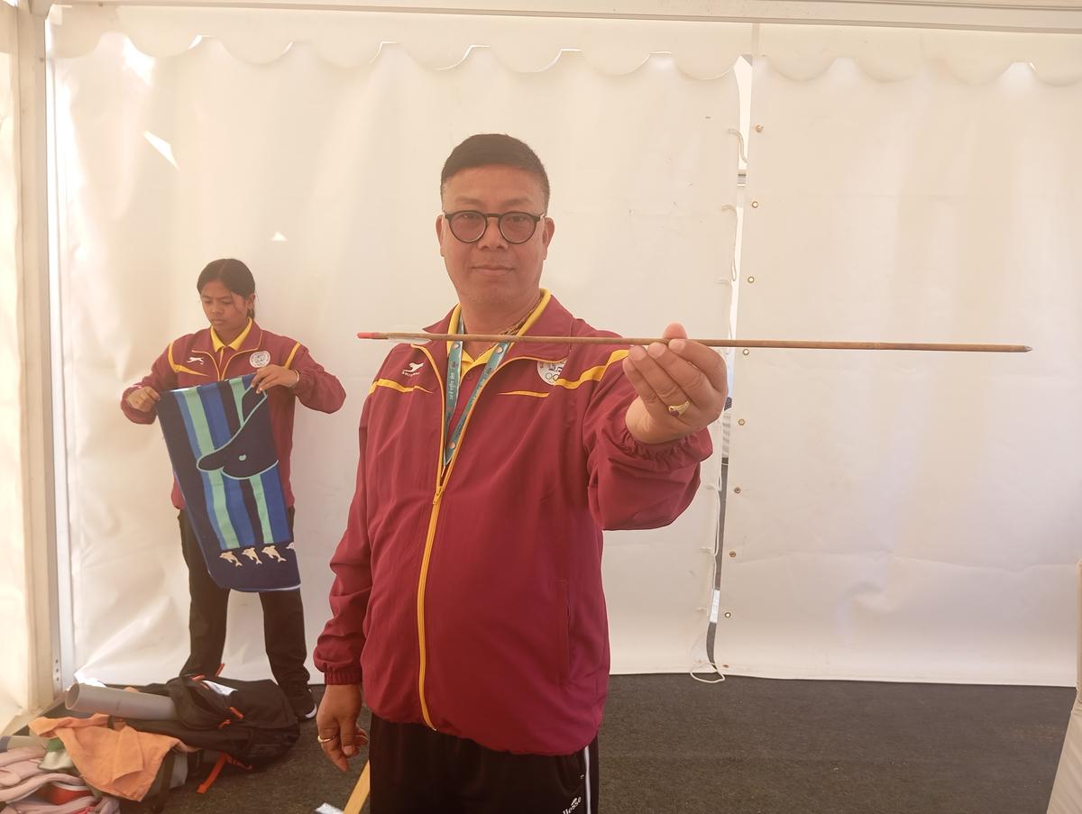 Manipur team manager Premkumar Sharma holding a bamboo arrow.