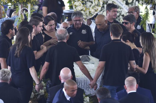 Edinho (3-L), prays with people during Pele’s 24-hour wake at the Vila Belmiro stadium.