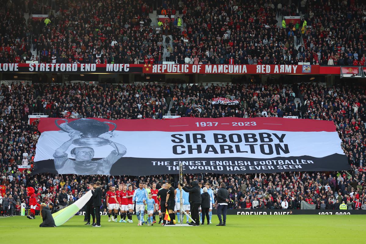 Fans hold up a flag in remembrance of Sir Bobby Charlton prior to the Premier League match between Manchester United and Manchester City at Old Trafford on October 29, 2023 in Manchester, England.