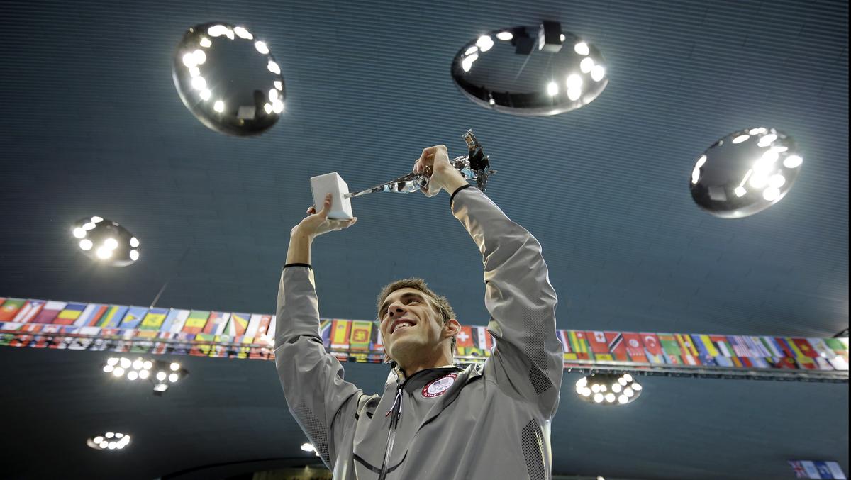 Michael Phelps holds up a silver trophy after being honoured as the most decorated Olympian during the 2012 Summer Olympics.