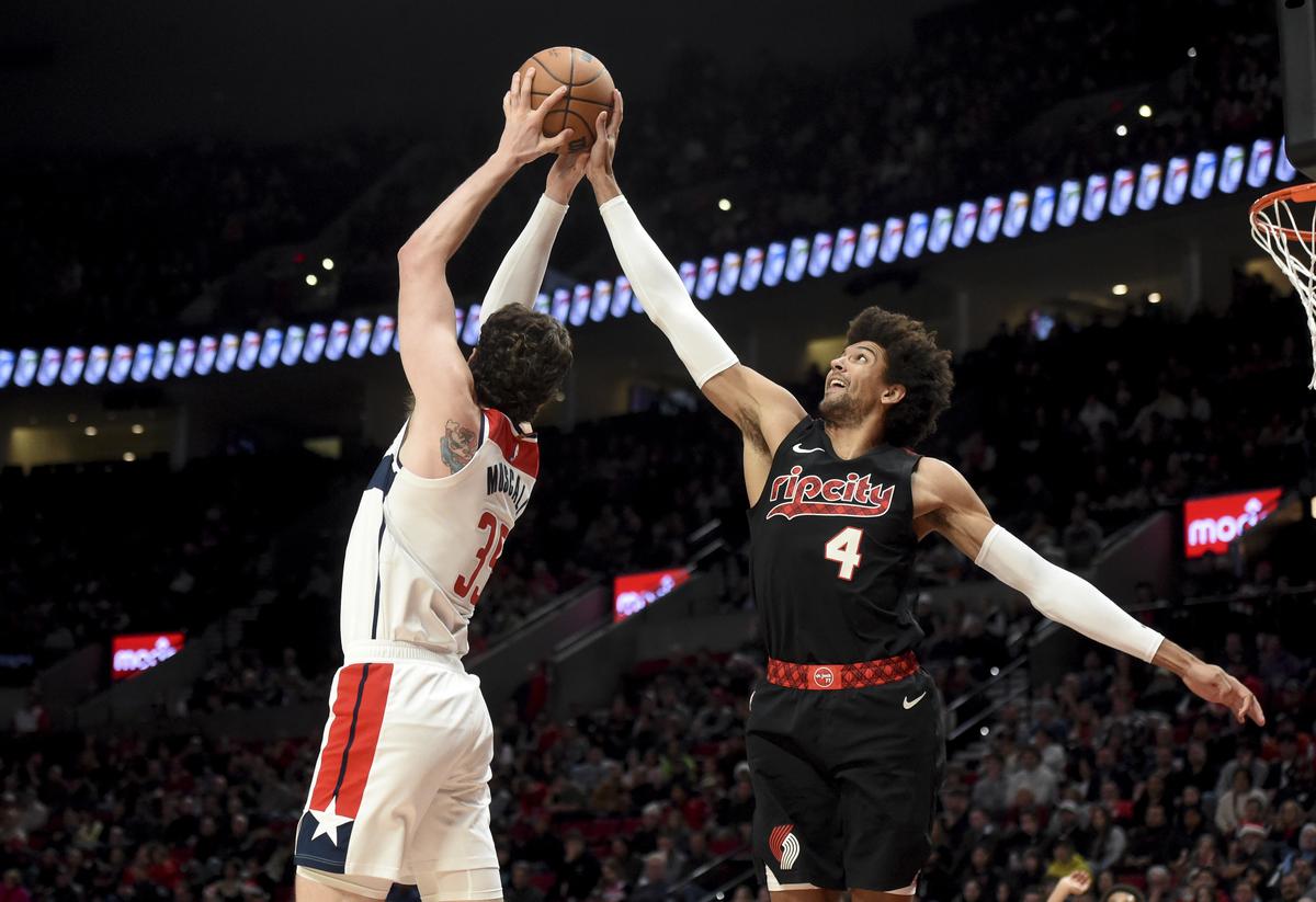 Portland Trail Blazers guard Matisse Thybulle, right, and Washington Wizards center Mike Muscala reach for a rebound during the second half of an NBA basketball game in Portland.