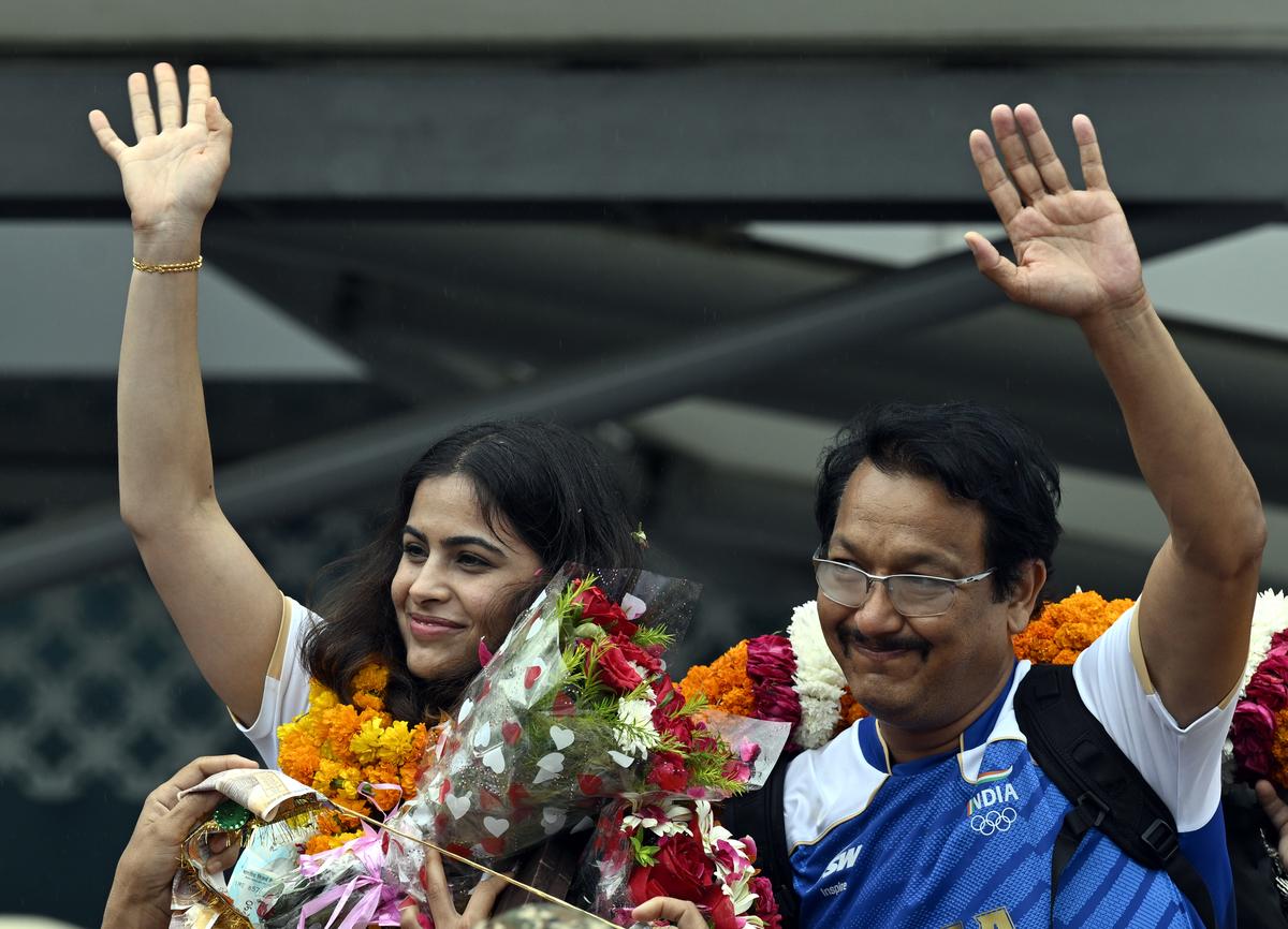 Bhaker with her personal coach Jaspal Rana, who won two bronze medals in the Olympics games being welcomed by family members and supporters during her arrival at the Indira Gandhi International Airport, New Delhi.