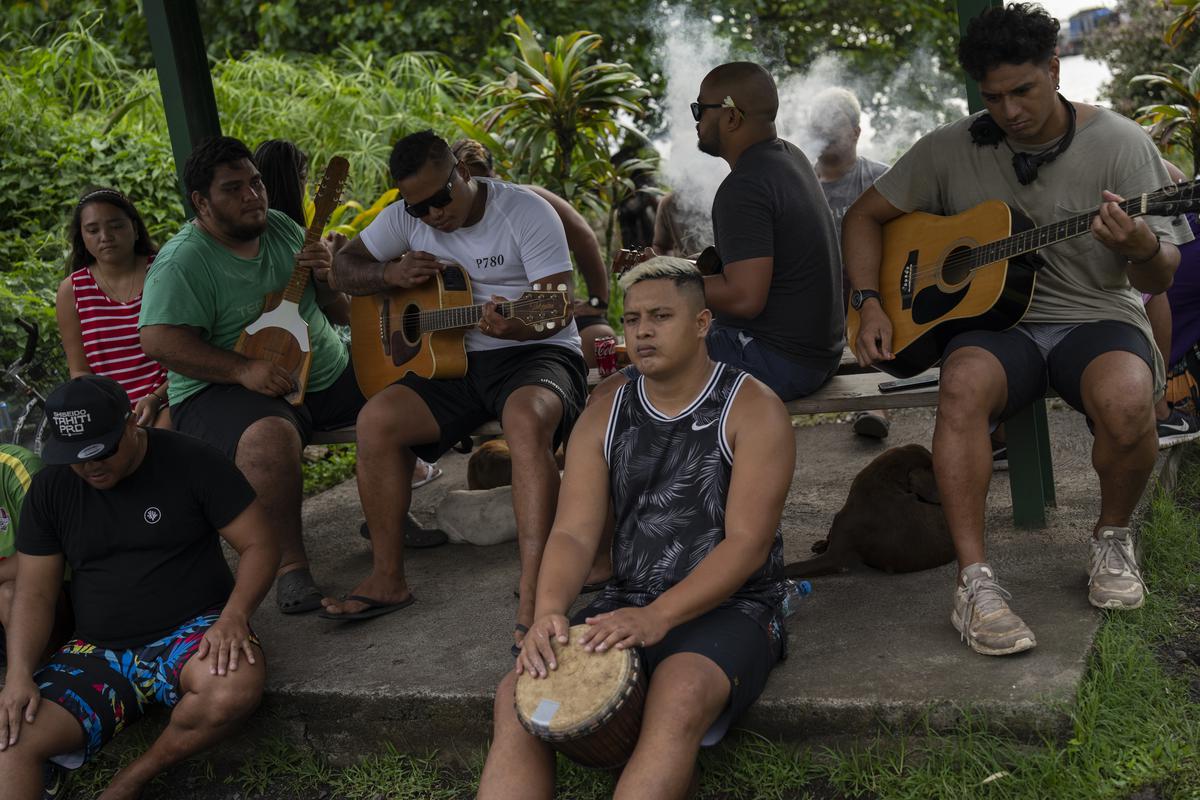 A group play music together by the side of the road in Teahupo’o, Tahiti, French Polynesia. The decision to host part of the Olympic Games here has thrust unprecedented challenges onto a small community that has long cherished and strives to protect its way of life. 