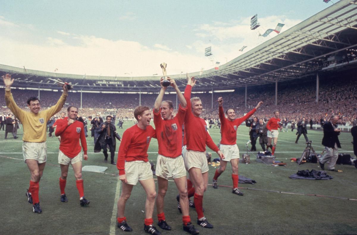 Bobby Charlton raises the World Cup trophy in the air  following England’s 4-2 victory after extra time over West Germany in the World Cup Final at Wembley Stadium, 30th July 1966. Amongst his team mates celebrating with him are goalkeeper Gordon Banks, Alan Ball on his right and team captain Bobby Moore (1941 - 1993) at his left. 