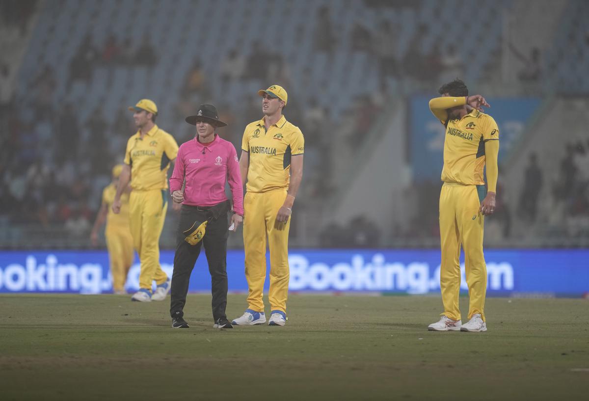 Australia’s Mitchell Starc, right, with captain Pat Cummins and umpire experience strong winds to interrupt the game during the ICC Men’s Cricket World Cup match between Australia and Sri Lanka. 