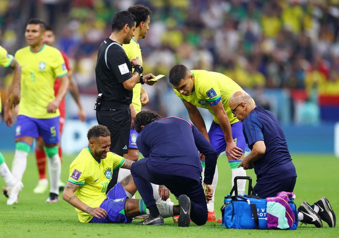 Le joueur vedette brésilien Neymar reçoit des soins médicaux après s'être blessé contre la Serbie sous le regard de Thiago Silva. 