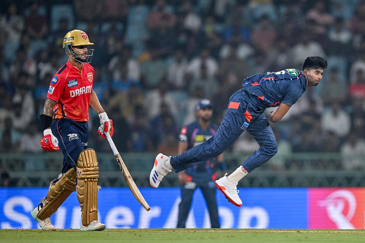 Lucknow Super Giants‘ Mayank Yadav bowls as Punjab Kings‘ captain Shikhar Dhawan watches. 