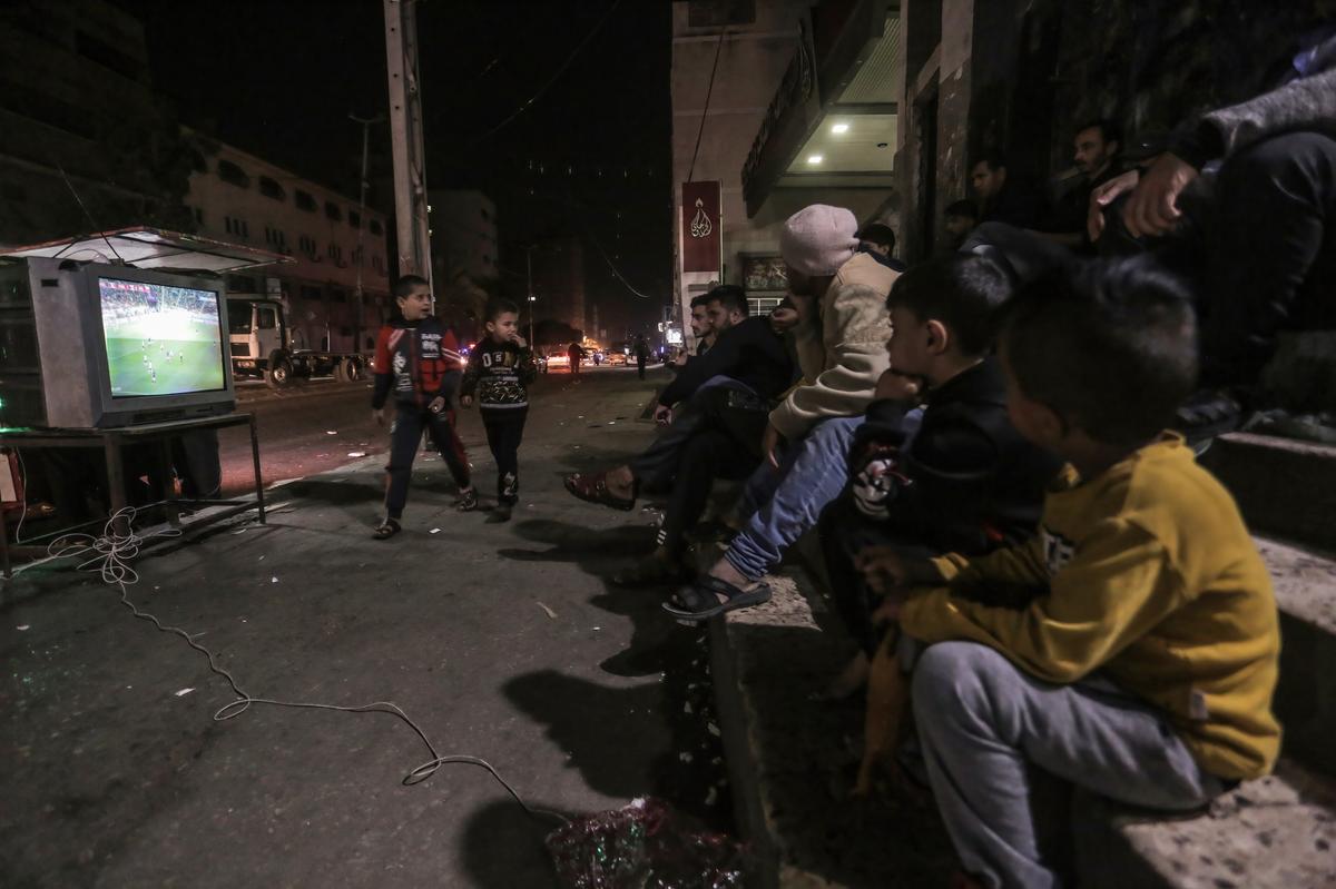 Les Palestiniens regardent un match de la Coupe du Monde de la FIFA entre la France et la Pologne sur la télévision de rue.