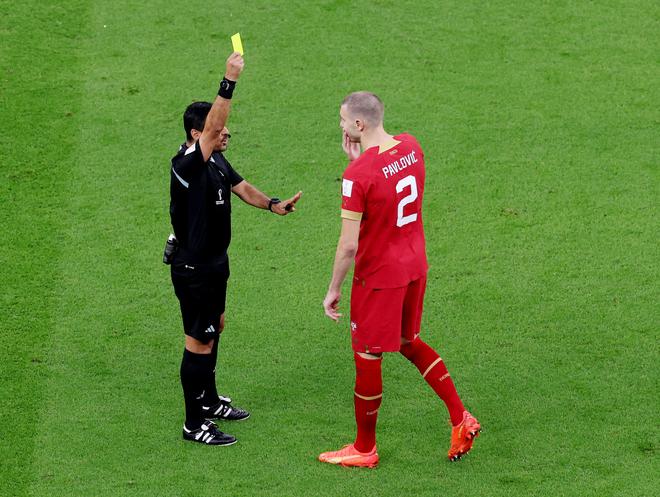 Serbia’a Strahinja Pavlovic is shown a yellow card by referee Alireza Faghani.