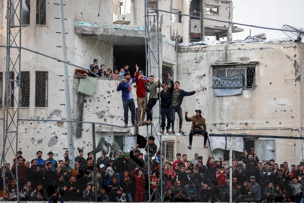 Chlapci vyliezli na rozbitú betónovú stenu alebo nazreli cez diery v ruinách, aby sa na to pozreli.