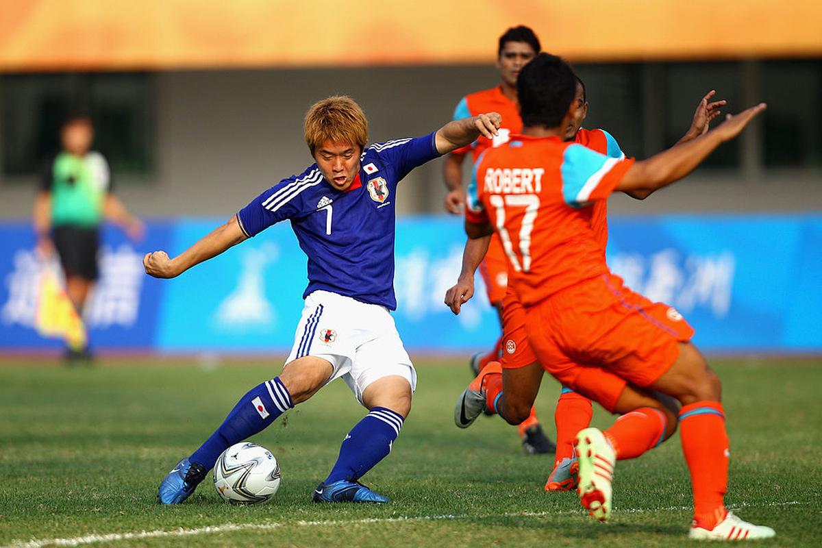 Ryohei Yamazaki of Japan tries to dribbled past Lalthlamuana of India in the round of 16 match between Japan and India at the 16th Asian Games in Guangzhou, China.