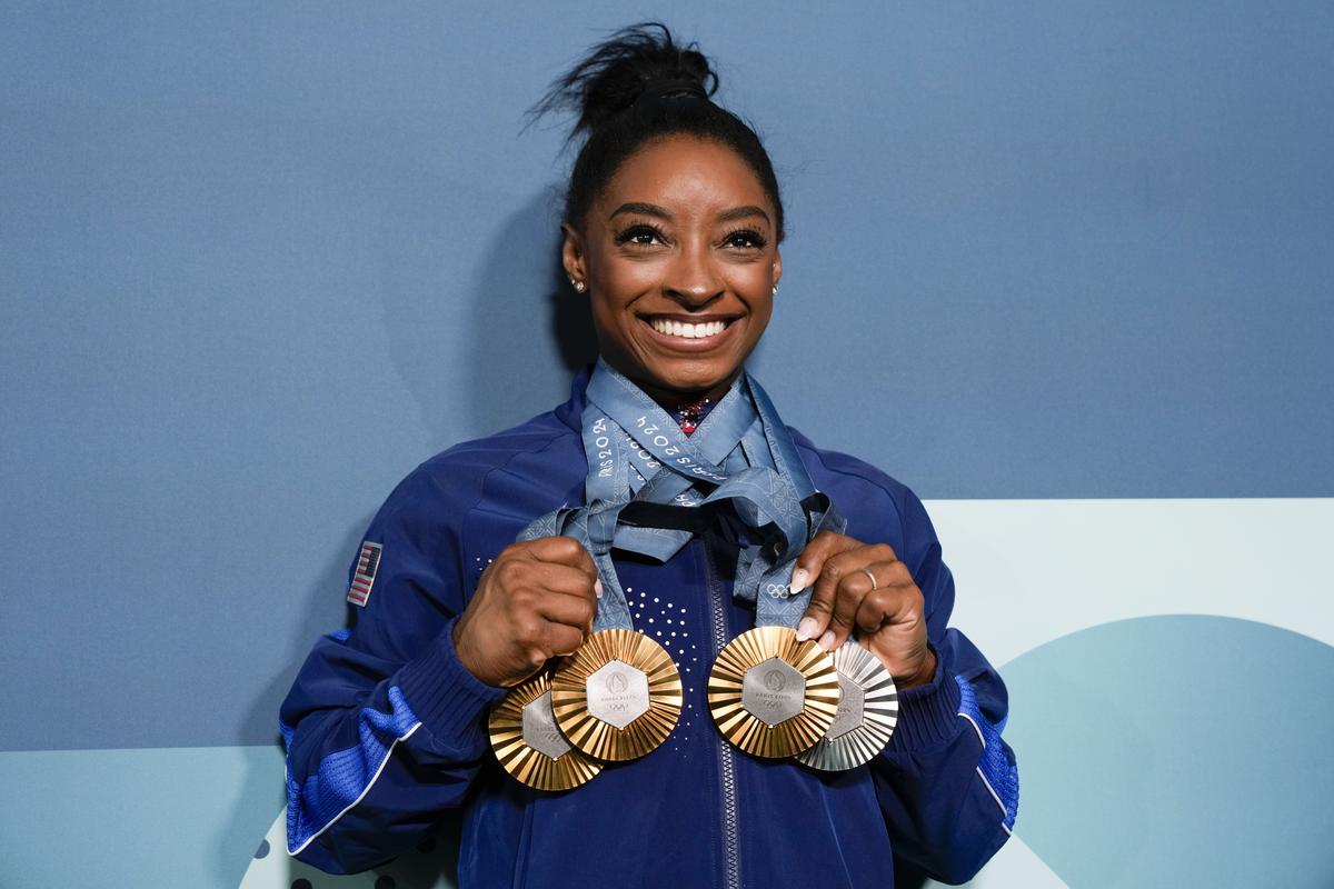 Simone Biles, of the United States, holds up her medals after the women’s artistic gymnastics individual apparatus finals.