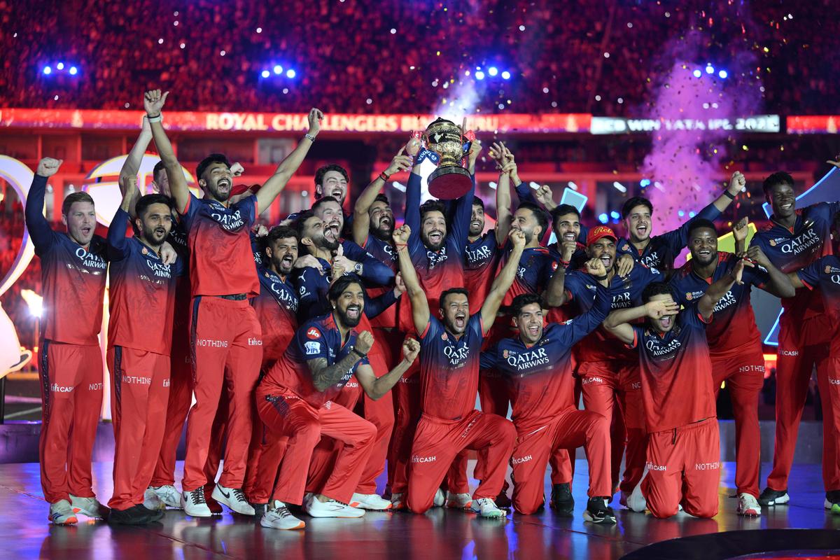 Royal Challengers Bangaluru captain Rajat Patidar lifts the IPL trophy, surrounded by teammates, after beating Punjab Kings in the final.